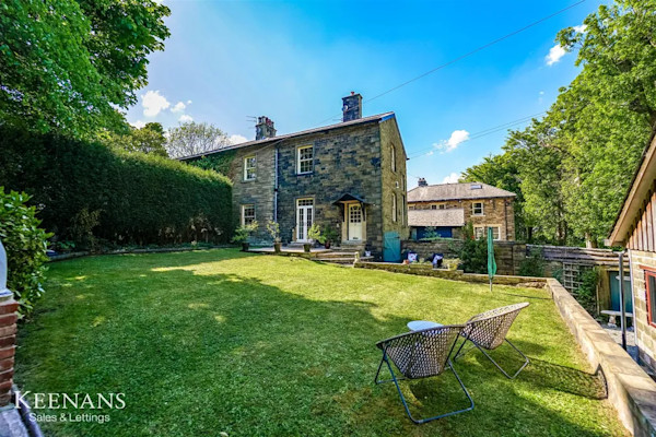 A rural stone cottage for sale with a large lawned garden and al-fresco seating area