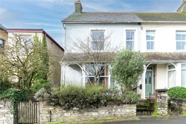 The exterior of a Victorian semi-detached house for sale in Liskeard with trees and bushes in the front garden giving it privacy