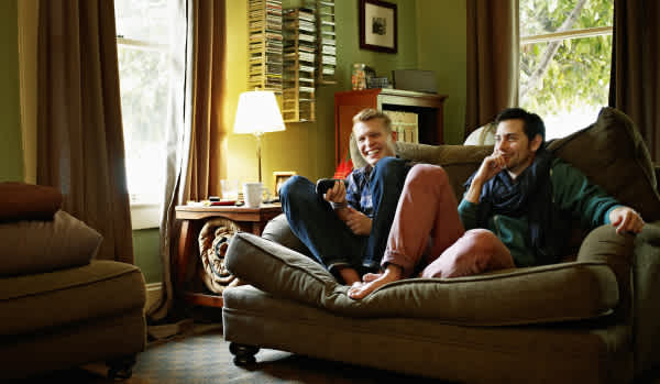 Young men relaxing on sofa at home