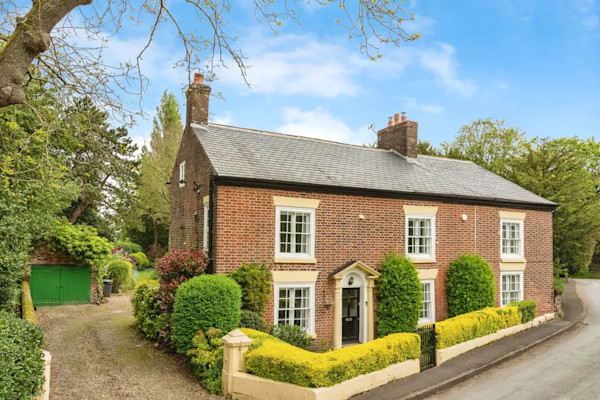 The exterior of a large characterful detached house in Warrington that sits close to the road with a stone driveway to the left