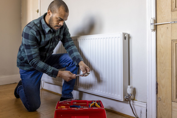 A man with a toolbox checking a radiator