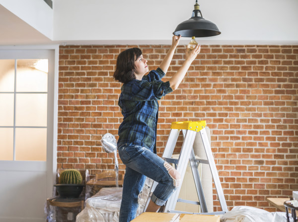 A woman changing a light bulb in her lounge