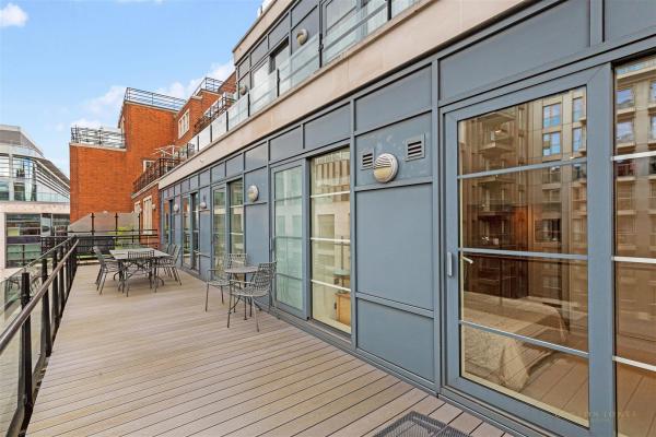 A large balcony with tables and chairs and big sliding doors leading into the two bedroom rental property in Westminster