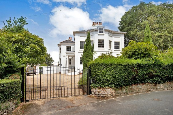 Outside shot of white, Georgian-style mansion with black steel gates