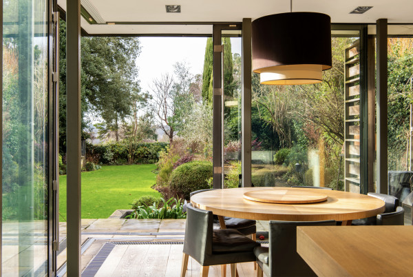 Modern dining room extension on a period house, with corner bifold doors leading to a lush garden