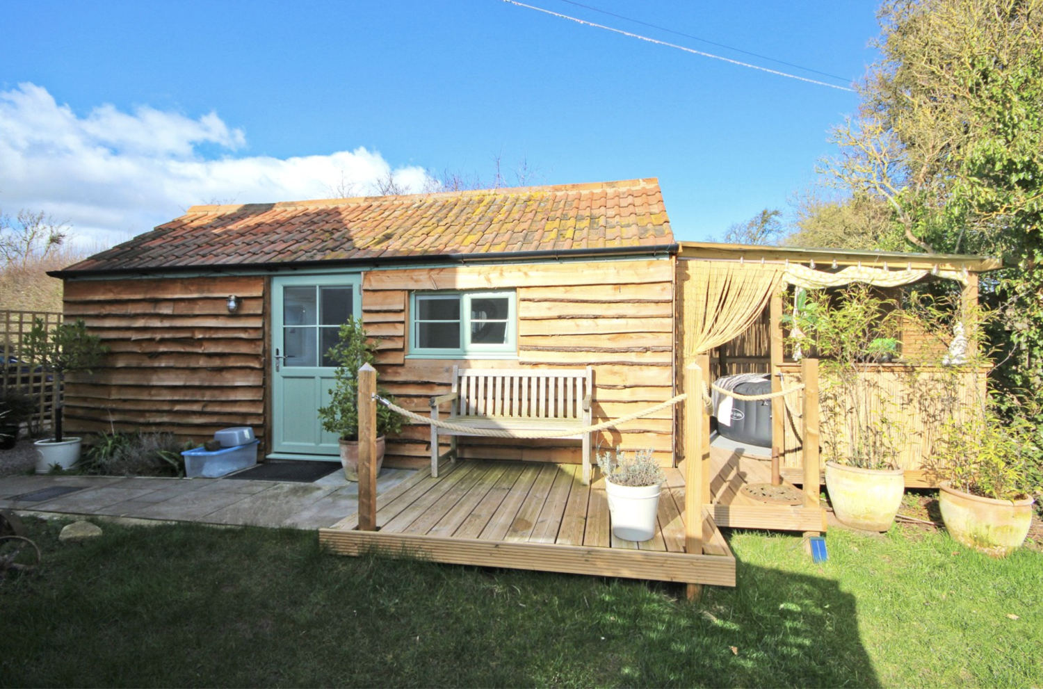 Wood cabin style annexe with a decked surround and a hot tub
