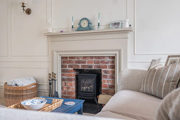 A close-up of a woodburner fire set within a neutral living room
