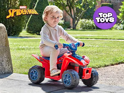 A boy sitting on the Spider-Man ATV Quad Bike 6V Electric Ride On in a garden.
