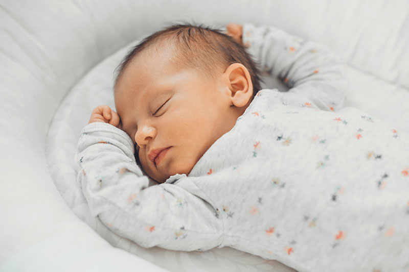 A baby asleep on a white mattress