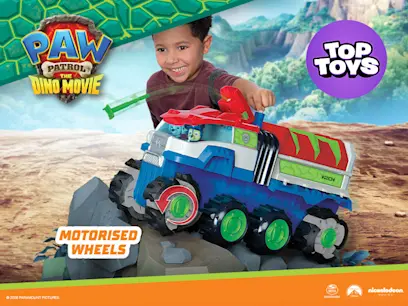 A kid playing with the PAW Patrol: The Dino Movie Ultimate Dino Hauler Motorised Vehicle on a Paw Patrol movie themed background.
