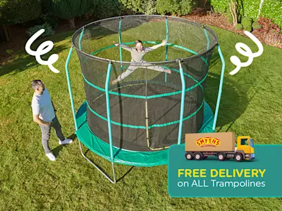 A child joyfully jumps on a trampoline in a sunny garden, observed by an adult. Text reads "Free delivery on all trampolines" with a toy truck graphic.