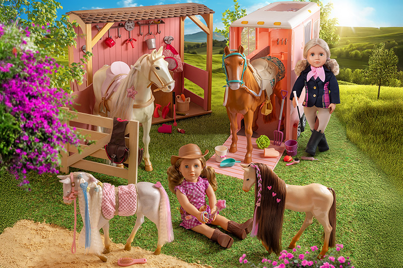 Our Generation Equestrian doll standing beside two horses in the Stables playset