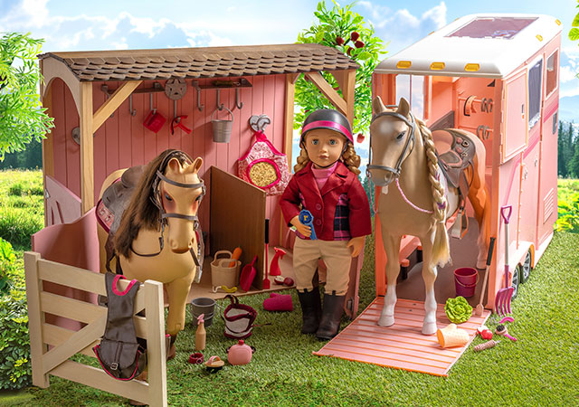 Our Generation Equestrian doll standing beside two horses in the Stables playset