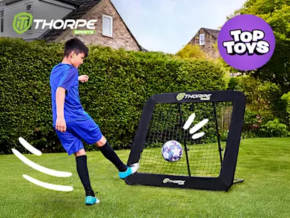 Boy kicking a football into the Thorpe Sports Adjustable Football Rebounder on a green grass in a garden