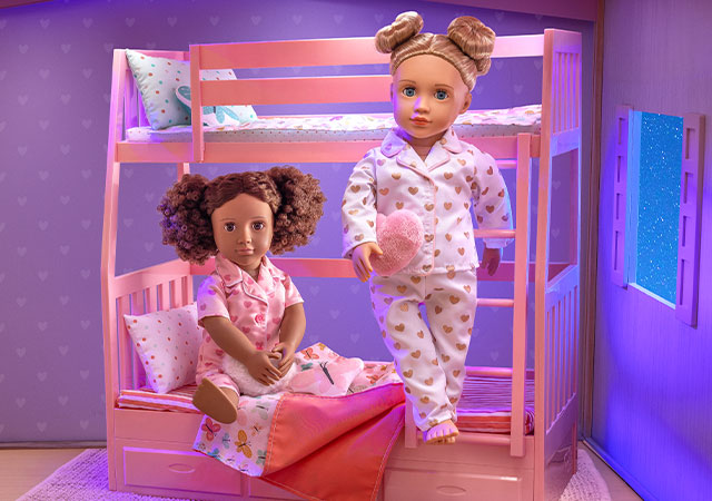 Our Generation doll standing beside and one doll sitting on a bunk beds