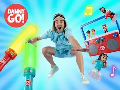 Danny Go jumping into the air with the Danny Go! Music Mix-Up Boombox and Colour Beat Drumsticks on a blue background behind him.