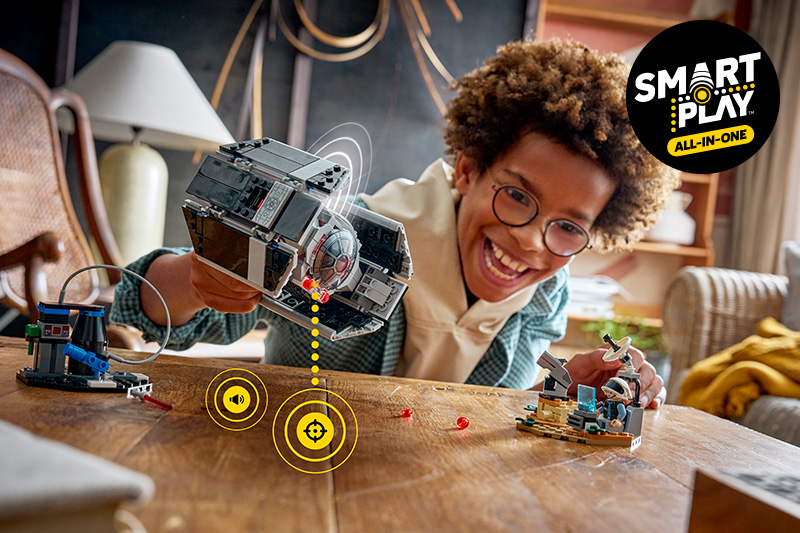 A kid building the LEGO Star Wars 75421 SMART Play: Darth Vader's TIE Fighter Set on a table.