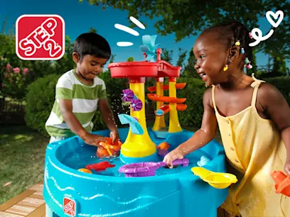 Girl and boy playing with the Step2 Archway Falls Water Table on a patio in a garden