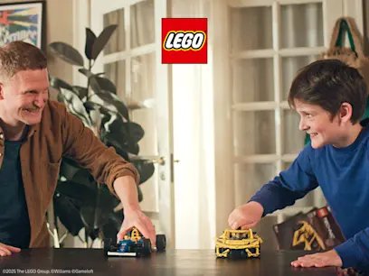 Man and boy playing together with two LEGO Technic cars on a table in a living room