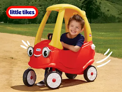 A boy playing in the Little Tikes Cozy Coupe Car Classic Ride On in a garden.