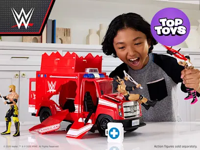A kid playing with the WWE Wrekkin Slambulance Breakaway Vehicle on a table in a bright room.