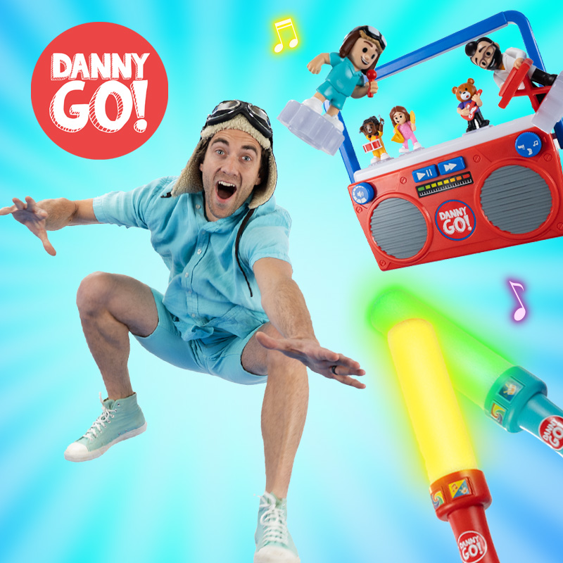 Danny Go jumping into the air with the Danny Go! Music Mix-Up Boombox and Colour Beat Drumsticks on a blue background behind him.