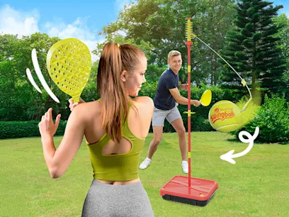 Kids playing swingball on green grass in a garden