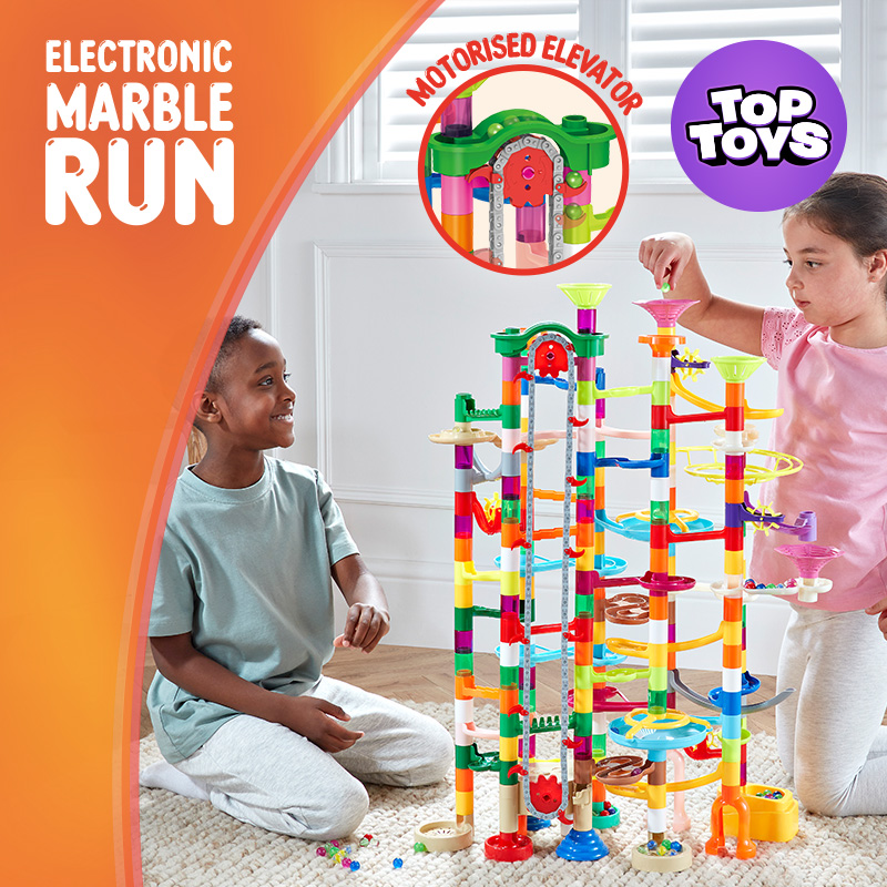 Children playing with a colourful electronic marble run toy indoors by a window.