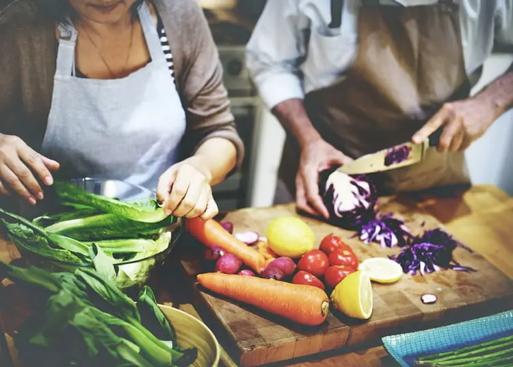 Pareja cortando vegetales frescos -  Alimentación saludable para adultos 