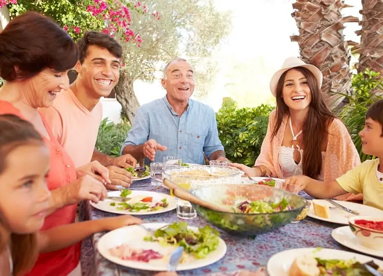 Adultos cenando sentados en la mesa, disfrutando de una comida saludable 