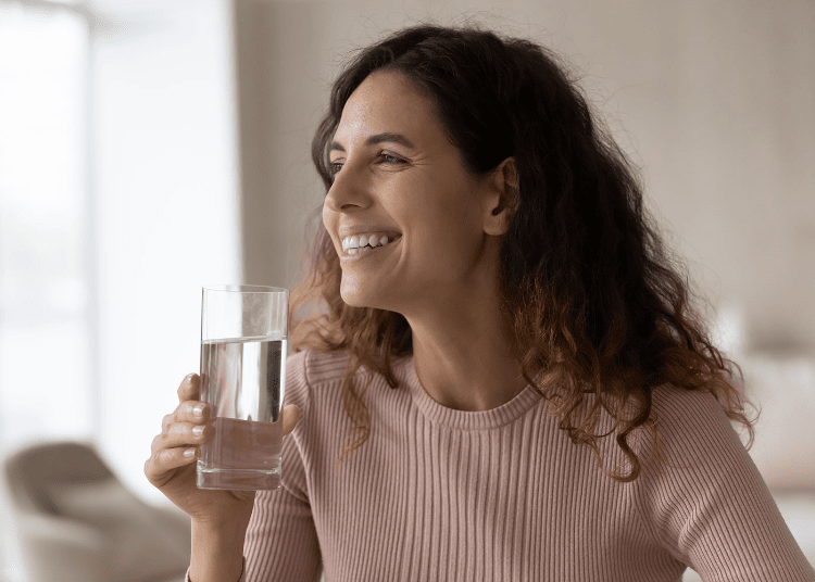 Mujer bebiendo agua rica en minerales para mantenerse en forma