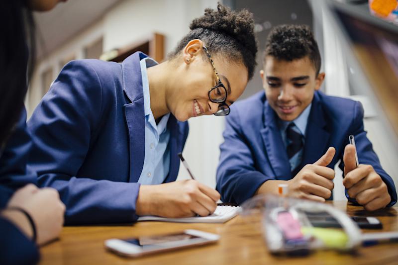 Teen students are working together and taking notes in lesson time at school.