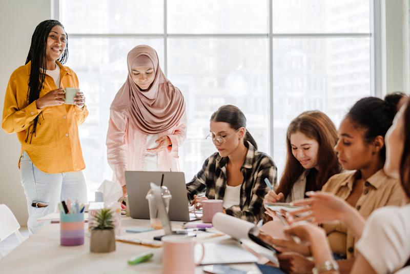 Multiracial young women discussing project during meeting indoors
