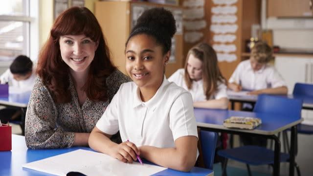 Primary school teacher and pupil in class looking to camera.