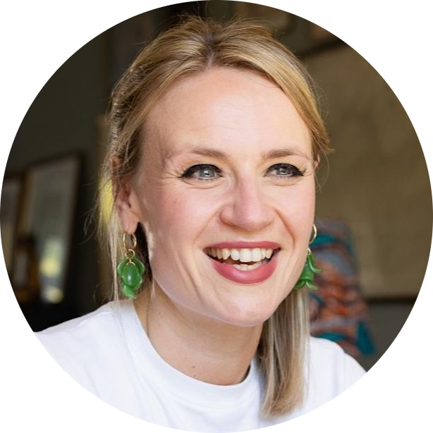 A headshot of Dr Camilla Rosan. She is smiling and wearing dangly green earrings.