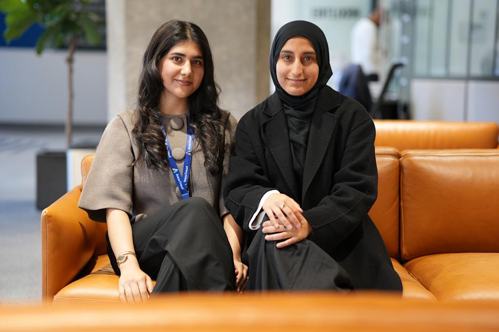 two female researchers sitting together on a sofa looking smiling at the camera