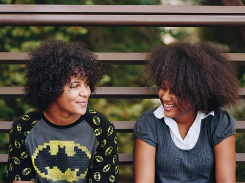 Two young people sitting next to each other smiling.