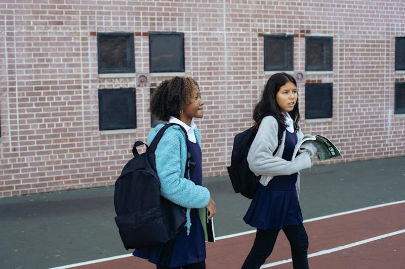 Two young people (of different ethnicity) in outdoor grounds of education setting.