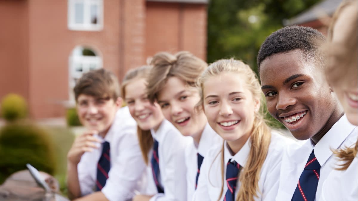 Five British secondary school children smiling, looking away from the camera.