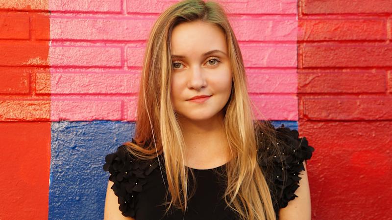 A young woman, facing the camera, smiling slightly.