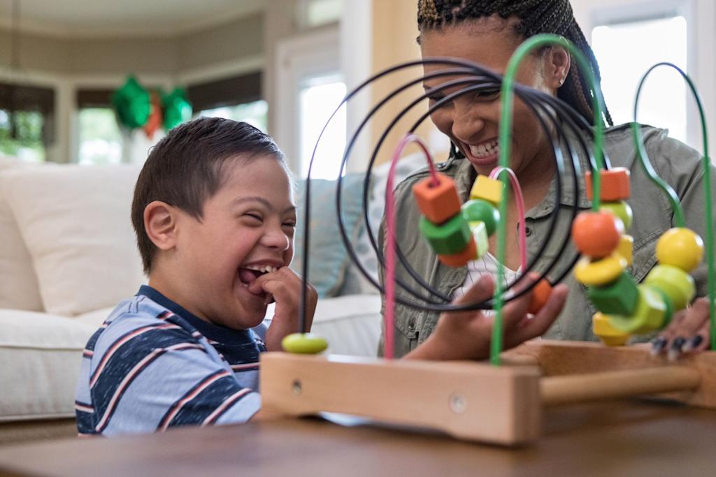 A young boy playing and laughing with an adult in a living room.