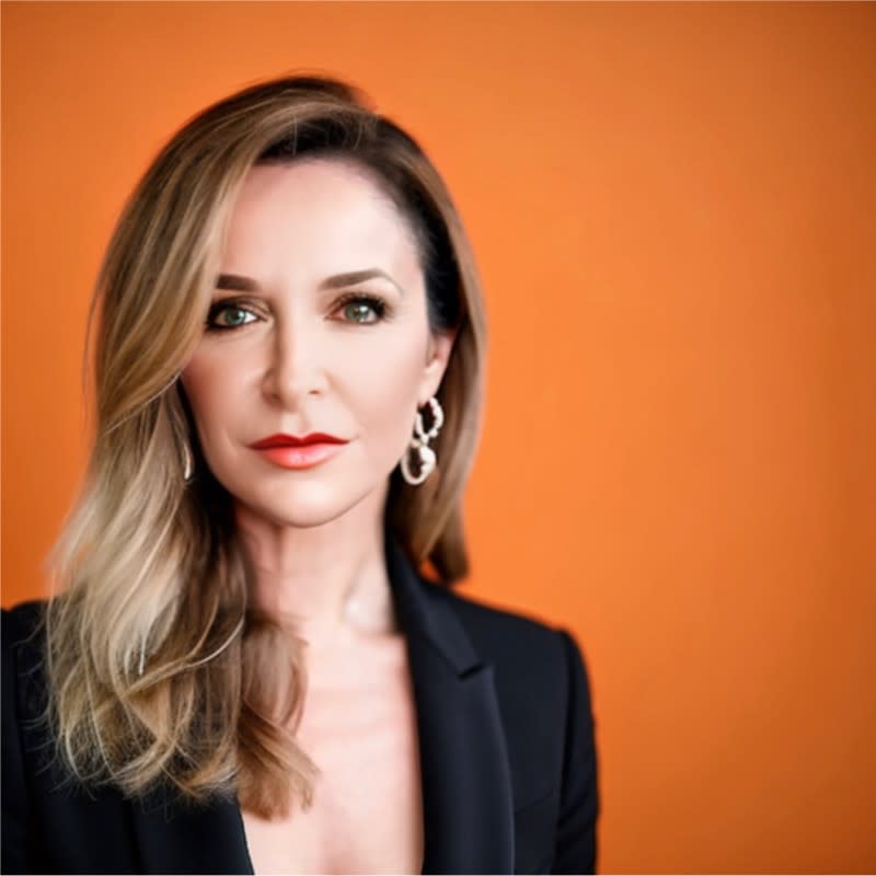 A headshot of Pamela Vona, standing against an orange backdrop.