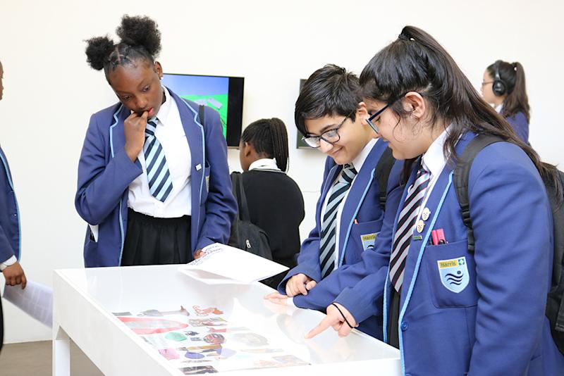 group of ethnically diverse pupils in uniform looking a display cabinet with interest