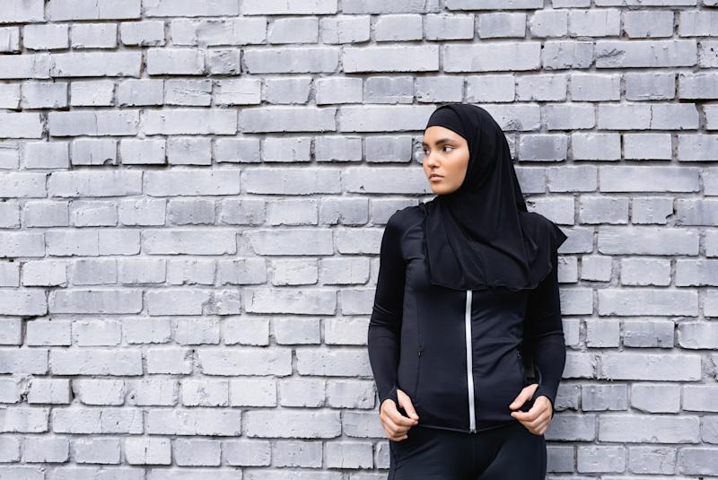 A young woman stands in front of a wall