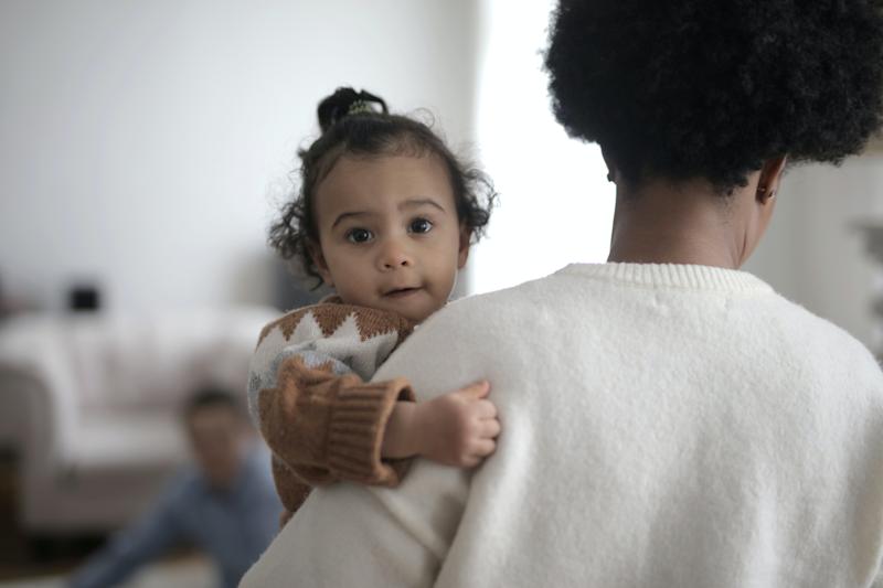 Baby facing the camera being held by mother.