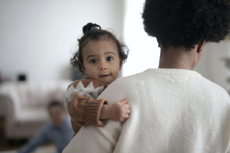 Baby facing the camera being held by mother.
