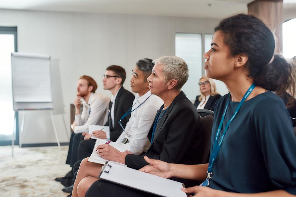 Get Together. Multi-ethnic audience sitting in a row while listening to presentation at conference hall