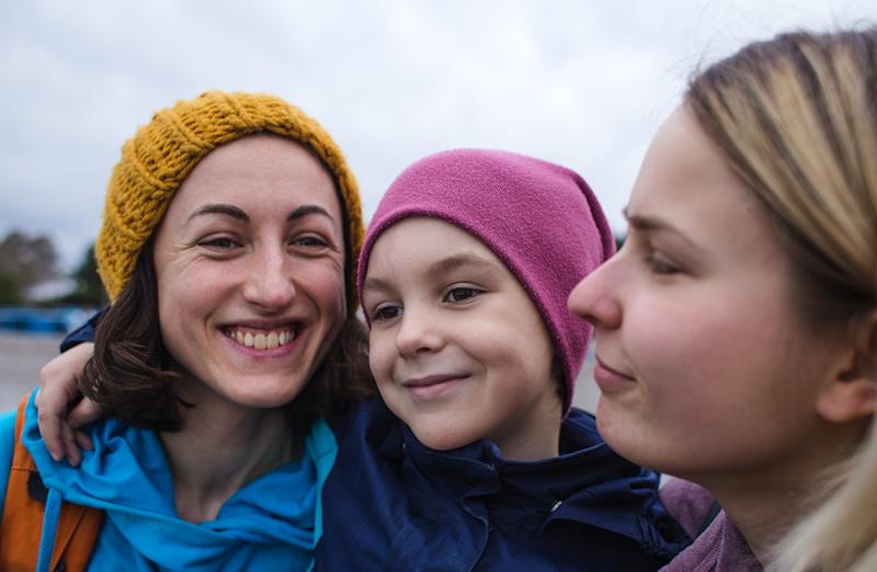 Two women with a child in-between them smiling.