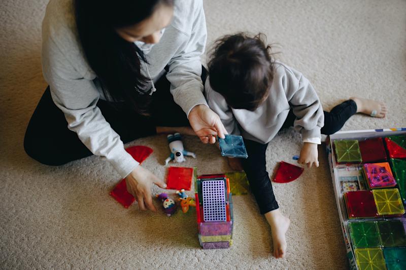 view from above of adult and young child playing with toys on a carpet