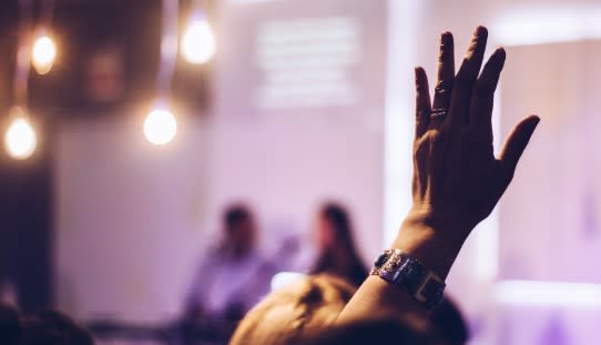 Person's hand help up as if asking a question at a conference